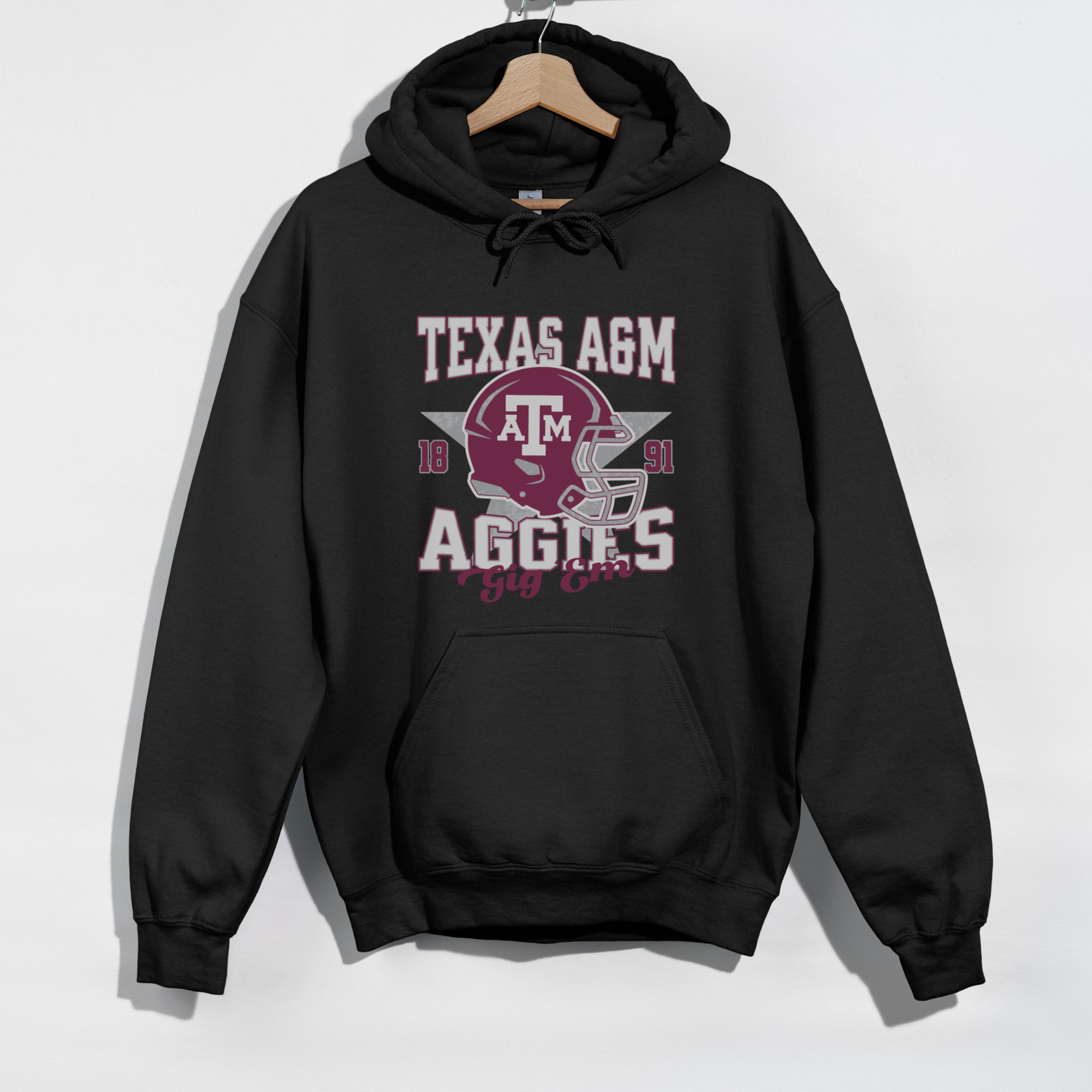 The Black Texas A&M Aggies Football Hoodie Sweatshirt lays flat on a white background. The Texas A&M Aggies Football graphic is in bold Unisex in a Varsity style.
