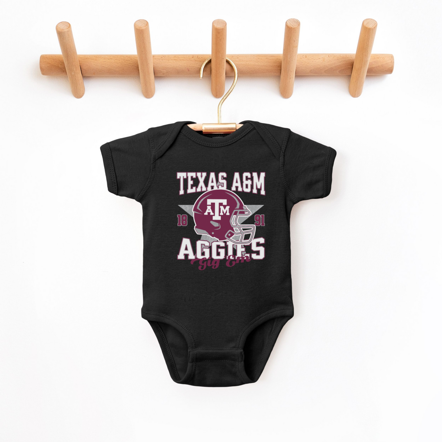 The Black Texas A&M Aggies Football Bodysuit lays flat on a white background. The Texas A&M Aggies Football graphic is in bold Multicolor in a Varsity style.