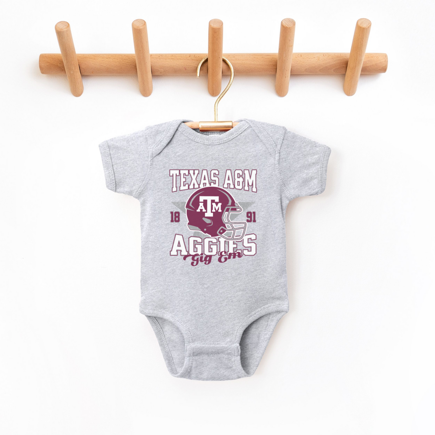 The Heather Grey Texas A&M Aggies Football Bodysuit lays flat on a white background. The Texas A&M Aggies Football graphic is in bold Multicolor in a Varsity style.