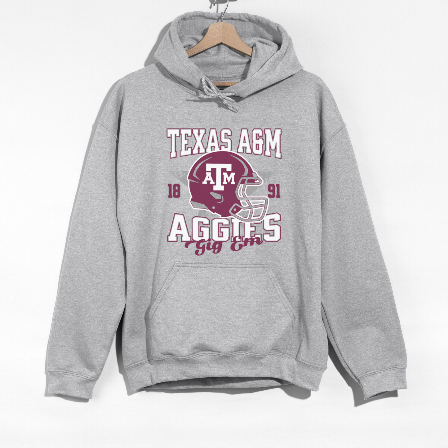 The Sport Grey Texas A&M Aggies Football Hoodie Sweatshirt lays flat on a white background. The Texas A&M Aggies Football graphic is in bold Unisex in a Varsity style.