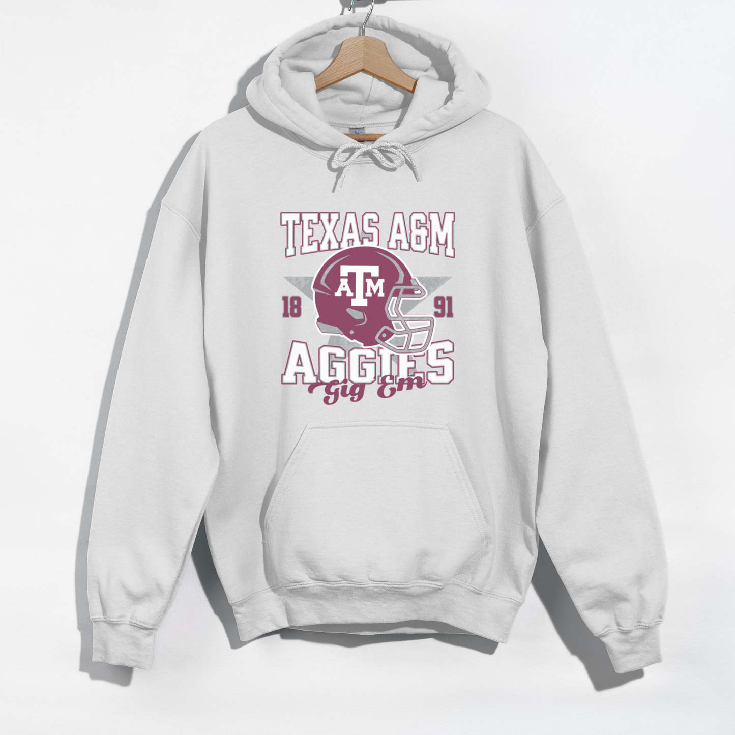 The White Texas A&M Aggies Football Hoodie Sweatshirt lays flat on a white background. The Texas A&M Aggies Football graphic is in bold Unisex in a Varsity style.