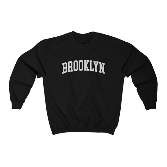 The Black Adult Unisex Brooklyn NY Collegiate Crewneck Sweatshirt lays flat on a white background. The ﻿Brooklyn NY Collegiate﻿ graphic is in bold White in a Varsity style.