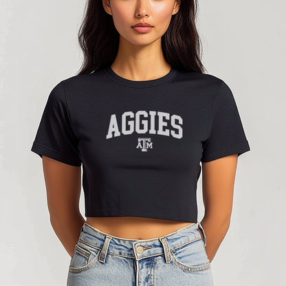 A model wears the Black Texas A&M Aggies Collegiate Crop Top.  The ﻿Texas A&M Aggies Collegiate﻿ graphic is in bold Maroon in a Varsity style.