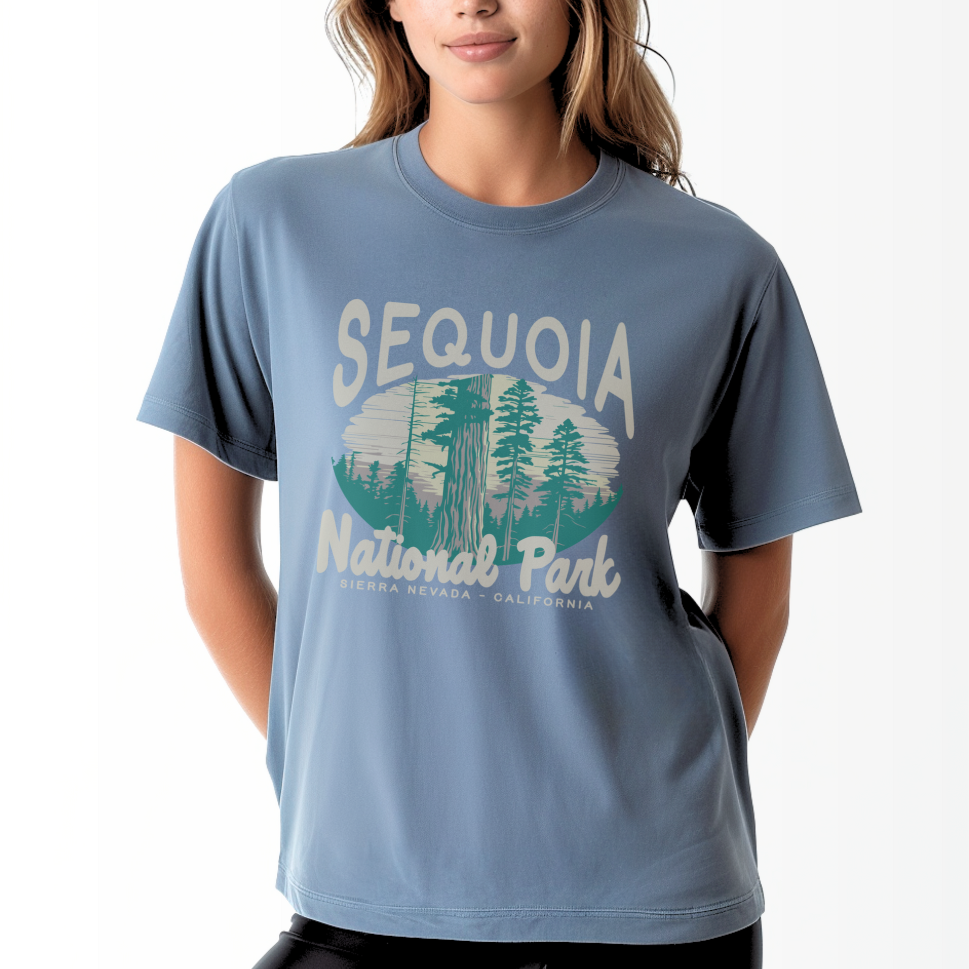 A model wears the Blue Jean Adult Unisex Sequoia National Park Comfort Colors T-shirt.  The ﻿Sequoia National Park﻿ graphic is in bold Lifestyle in a Rustic Park style.