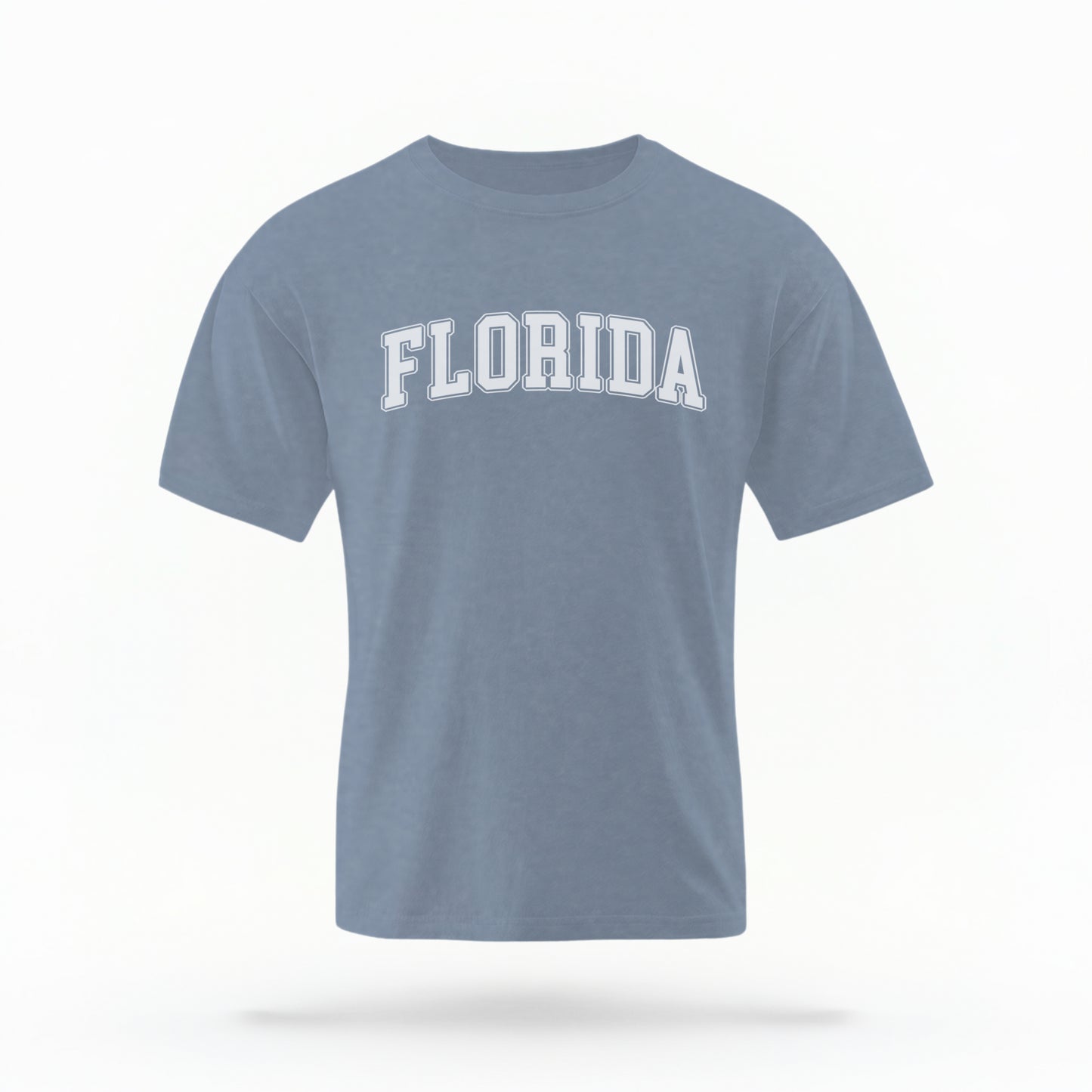 The blue jeans Adult Unisex Florida Varsity Comfort Colors T-shirt lays flat on a white background. The Florida graphic is in bold white in a varsity offset style.
