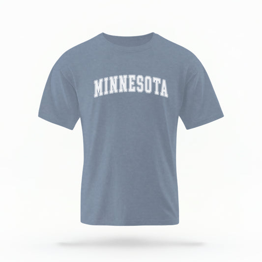 The Blue Jeans Unisex Minnesota Varsity Comfort Colors T-shirt lays flat on a white background. The Minnesota graphic is in bold white in a varsity offset style.
