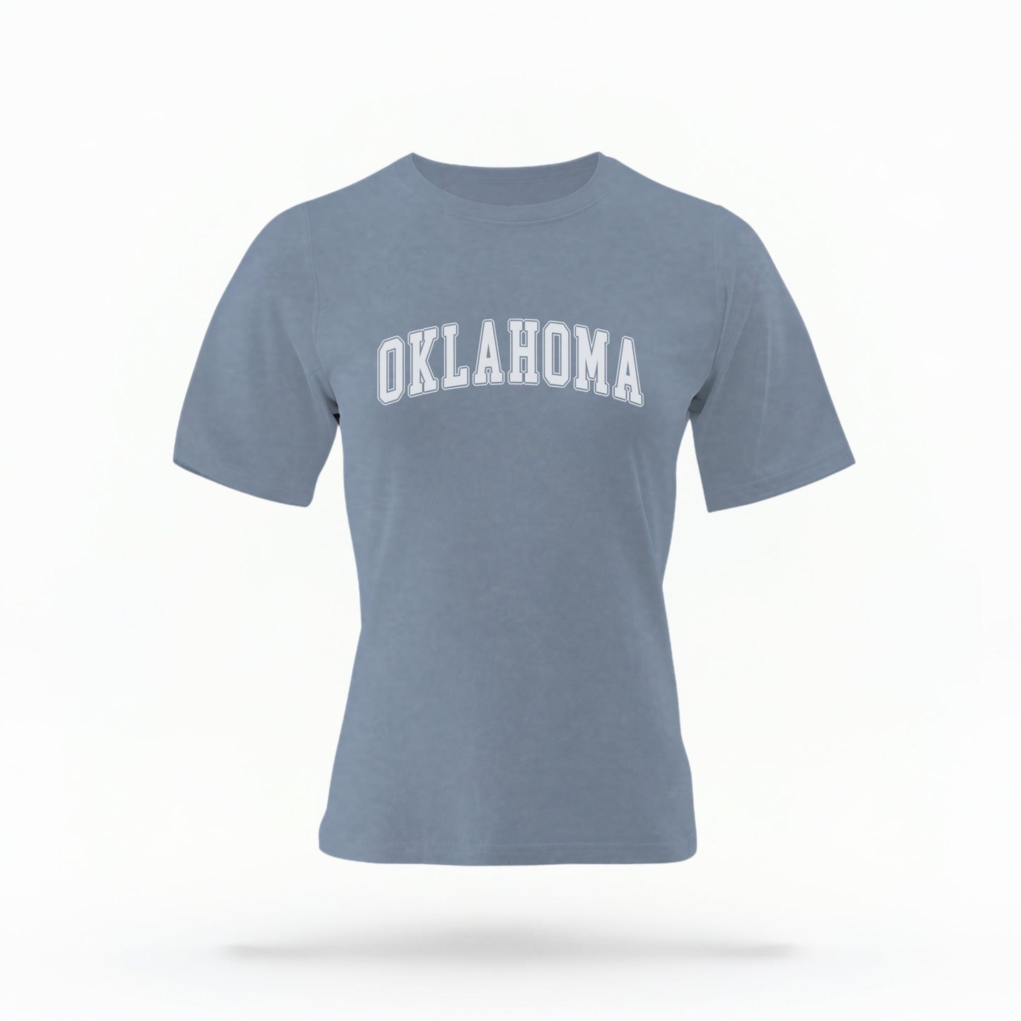 The Blue Jeans Unisex Oklahoma Varsity Comfort Colors T-shirt lays flat on a white background. The Oklahoma graphic is in bold white in a varsity offset style.