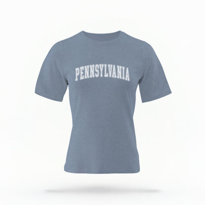 The Blue Jeans Unisex Pennsylvania Varsity Comfort Colors T-shirt lays flat on a white background. The Pennsylvania graphic is in bold white in a varsity offset style.
