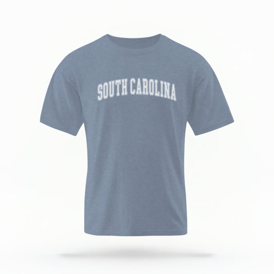 The Blue Jeans Unisex South Carolina Varsity Comfort Colors T-shirt lays flat on a white background. The South Carolina graphic is in bold white in a varsity offset style.