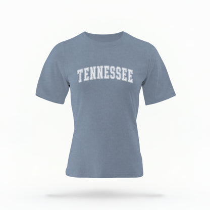 The Blue Jeans Unisex Tennessee Varsity Comfort Colors T-shirt lays flat on a white background. The Tennessee graphic is in bold white in a varsity offset style.