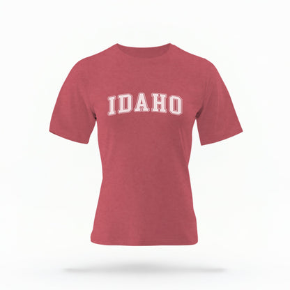 The Crimson Unisex Idaho Varsity Comfort Colors T-shirt lays flat on a white background. The Idaho graphic is in bold white in a varsity offset style.