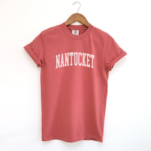 The Crimson Adult Unisex Nantucket Massachusetts Varsity Comfort Colors T-shirt lays flat on a white background. The ﻿Nantucket Massachusetts Varsity﻿ graphic is in bold White in a Collegiate Block style.