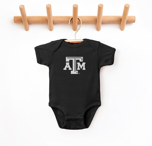 The Black Infant Unisex Texas A&M Logo Bodysuit lays flat on a white background. The ﻿Texas A&M Logo﻿ graphic is in bold White in a Varsity style.