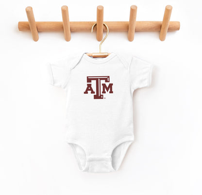 The White Infant Unisex Texas A&M Logo Bodysuit lays flat on a white background. The ﻿Texas A&M Logo﻿ graphic is in bold Maroon in a Varsity style.