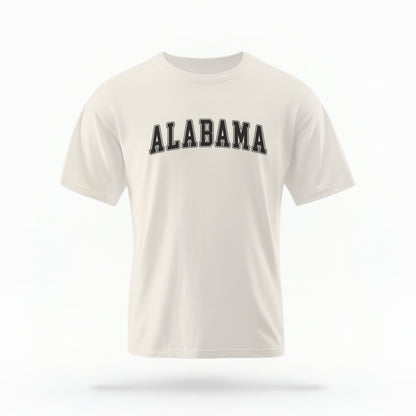 The ivory Unisex Alabama Varsity Comfort Colors T-shirt lays flat on a white background. The Alabama graphic is in bold black in a varsity offset style.