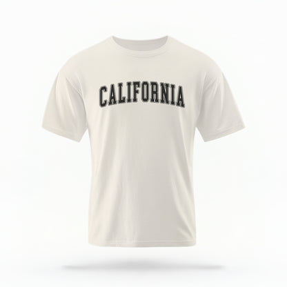 The Ivory California Varsity Comfort Colors T-shirt lays flat on a white background. The ﻿California Varsity﻿ graphic is in bold Black in a Varsity style.