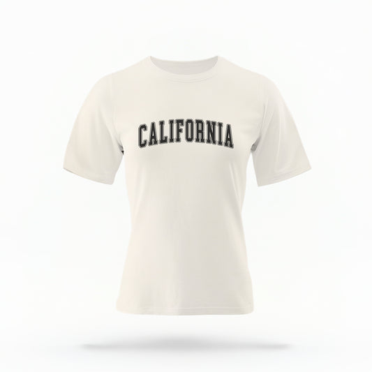 The Ivory California Varsity Comfort Colors T-shirt lays flat on a white background. The ﻿California Varsity﻿ graphic is in bold White in a Varsity style.