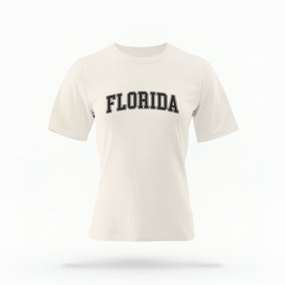 The ivory Adult Unisex Florida Varsity Comfort Colors T-shirt lays flat on a white background. The Florida graphic is in bold white in a varsity offset style.