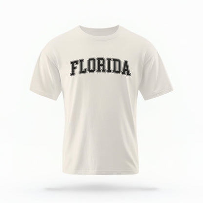 The ivory Adult Unisex Florida Varsity Comfort Colors T-shirt lays flat on a white background. The Florida graphic is in bold black in a varsity offset style.