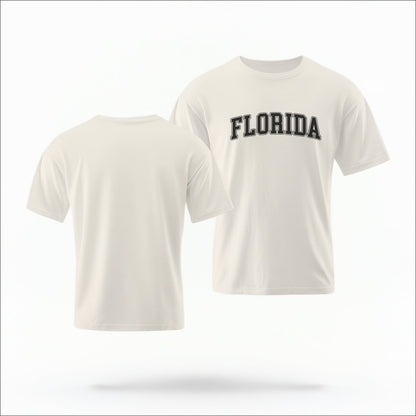 The ivory Adult Unisex Florida Varsity Comfort Colors T-shirt lays flat on a white background. The Florida graphic is in bold white in a varsity offset style.