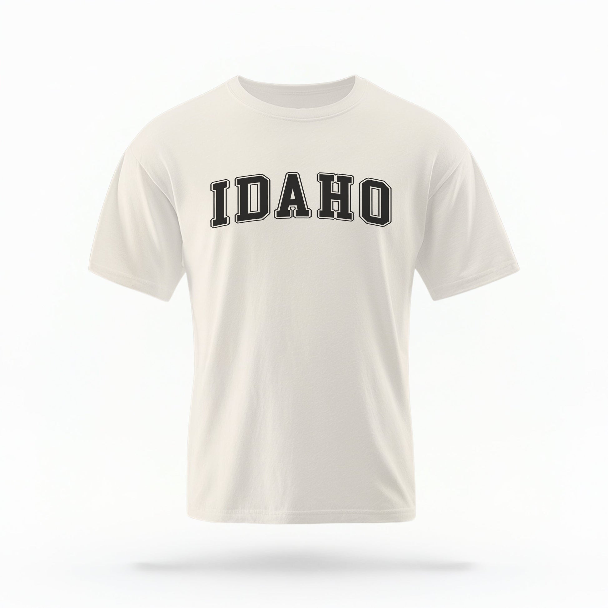 The ivory Unisex Idaho Varsity Comfort Colors T-shirt lays flat on a white background. The Idaho graphic is in bold black in a varsity offset style.