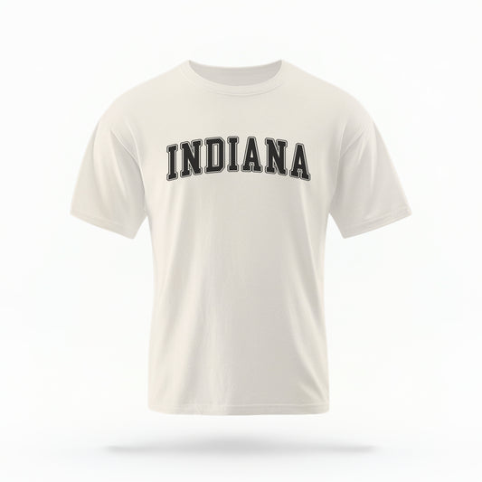 The ivory Unisex Indiana Varsity Comfort Colors T-shirt lays flat on a white background. The Indiana graphic is in bold black in a varsity offset style.