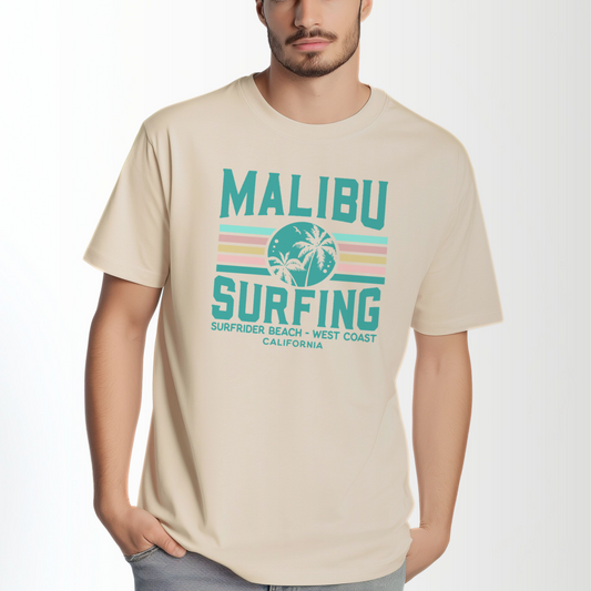 A model wears the Ivory Adult Unisex Malibu California Surfing Comfort Colors T-shirt.  The ﻿Malibu California Surfing﻿ graphic is in bold Lifestyle in a Multicolor style.