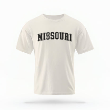 The Ivory Unisex Missouri Varsity Comfort Colors T-shirt lays flat on a white background. The Missouri graphic is in bold black in a varsity offset style.