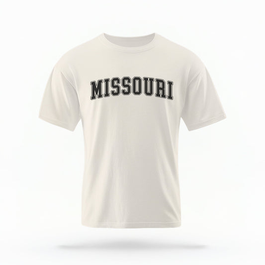 The Ivory Unisex Missouri Varsity Comfort Colors T-shirt lays flat on a white background. The Missouri graphic is in bold black in a varsity offset style.