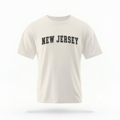 The ivory Unisex New Jersey Varsity Comfort Colors T-shirt lays flat on a white background. The New Jersey graphic is in bold black in a varsity offset style.