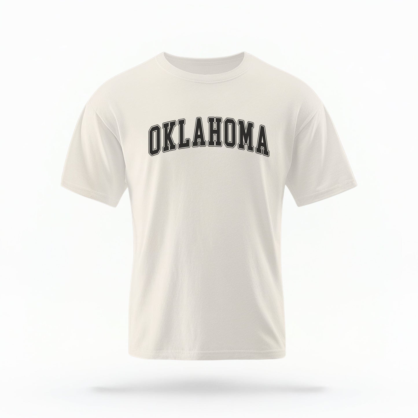 The ivory Unisex Oklahoma Varsity Comfort Colors T-shirt lays flat on a white background. The Oklahoma graphic is in bold black in a varsity offset style.