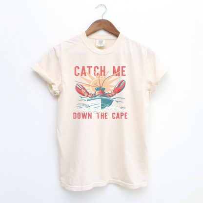 The Ivory Adult Unisex Catch Me Down The Cape Comfort Colors T-shirt lays flat on a white background. The ﻿Catch Me Down The Cape﻿ graphic is in bold multicolor in a Vintage style.