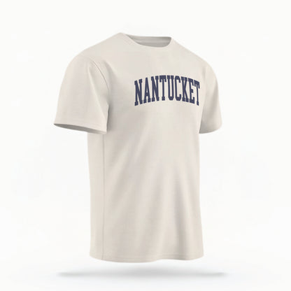 The ivory Unisex Nantucket Varsity Comfort Colors T-shirt lays flat on a white background. The Nantucket graphic is in bold navy in a varsity offset style.