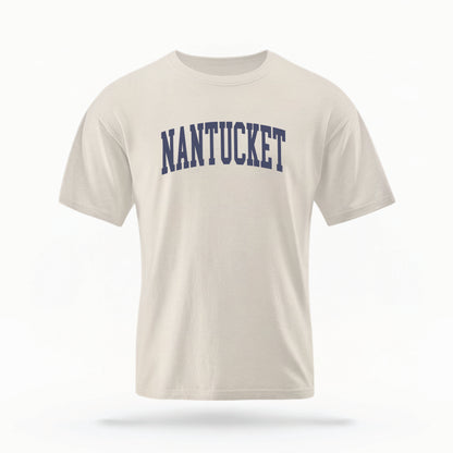 The Ivory Adult Unisex Nantucket Massachusetts Varsity Comfort Colors T-shirt lays flat on a white background. The ﻿Nantucket Massachusetts Varsity﻿ graphic is in bold Navy in a Collegiate Block style.