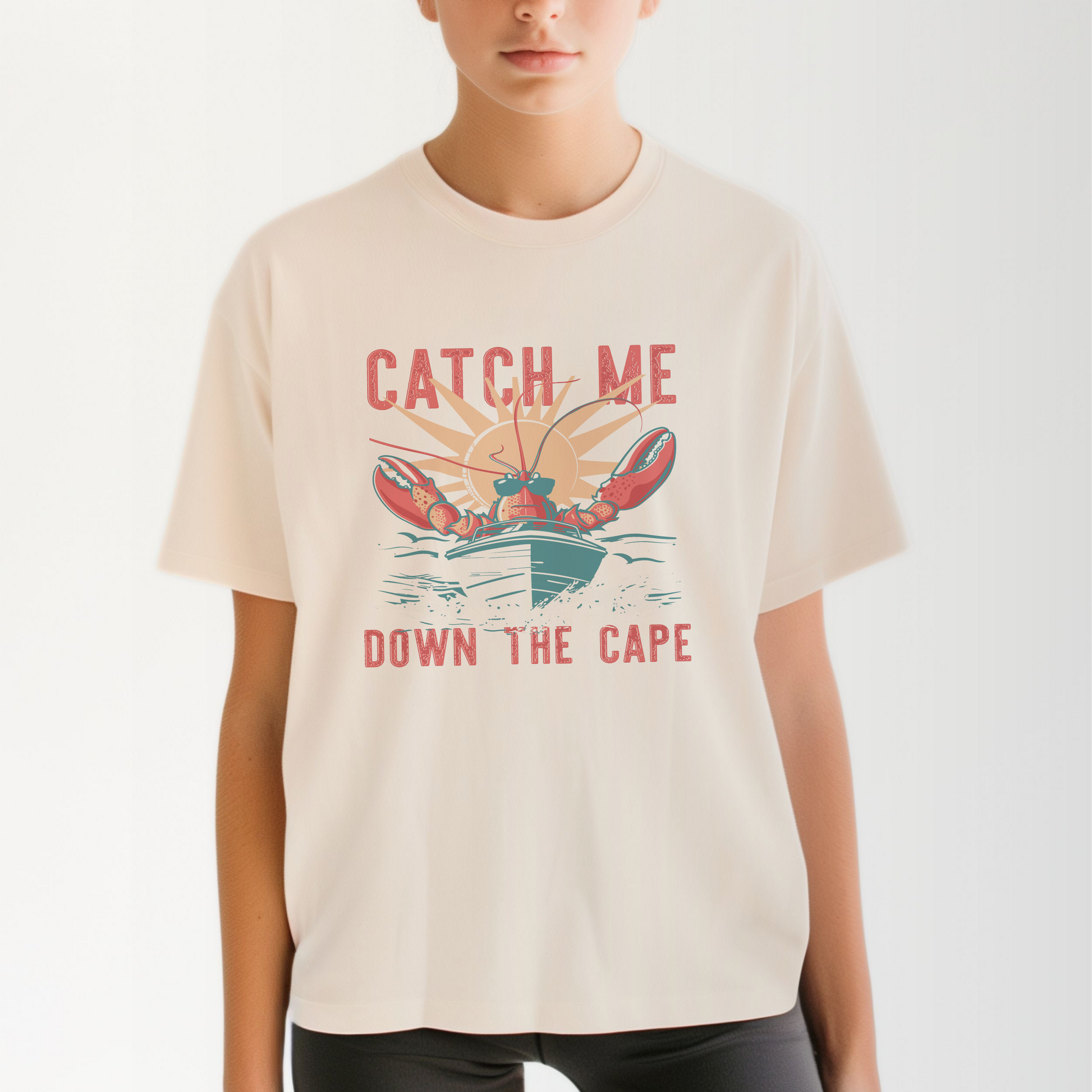 A model wears the Ivory Adult Unisex Catch Me Down The Cape Comfort Colors T-shirt.  The ﻿Catch Me Down The Cape﻿ graphic is in bold multicolors in a Vintage style.