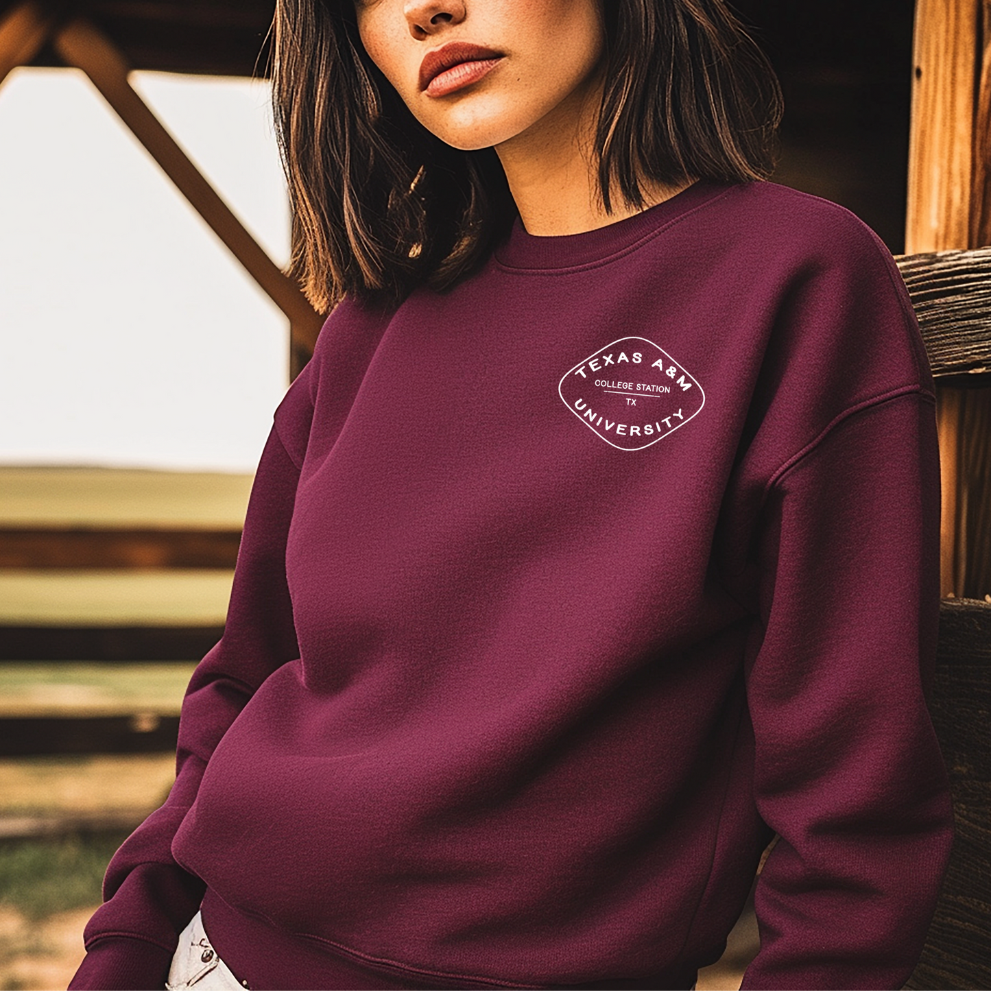A model wears the maroon Texas A&M Crewneck Sweatshirt. The graphic contains a retro checkered pattern. 