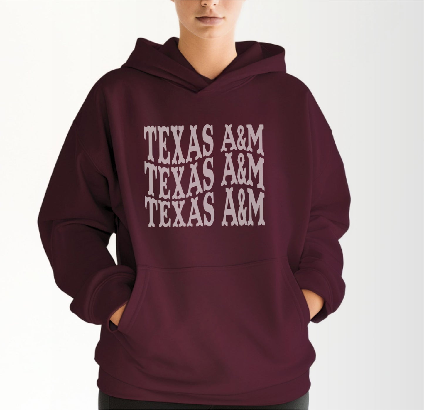 A model wears the Maroon Adult Unisex Texas A&M Western Hooded Sweatshirt.  The ﻿Texas A&M Western﻿ graphic is in bold White in a Western style.