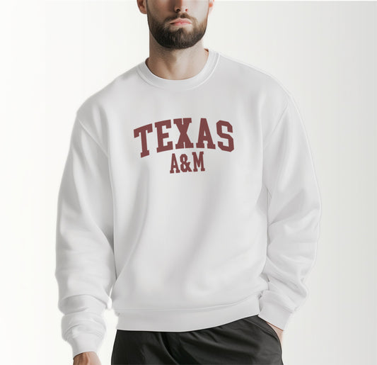 A model wears the White Adult Unisex Texas A&M Varsity Crewneck Sweatshirt.  The ﻿Texas A&M Varsity﻿ graphic is in bold Maroon in a Collegiate style.
