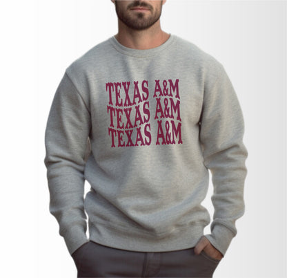 A model wears the Sport Grey Adult Unisex Texas A&M Western Crewneck Sweatshirt.  The ﻿Texas A&M Western﻿ graphic is in bold Maroon in a Western style.