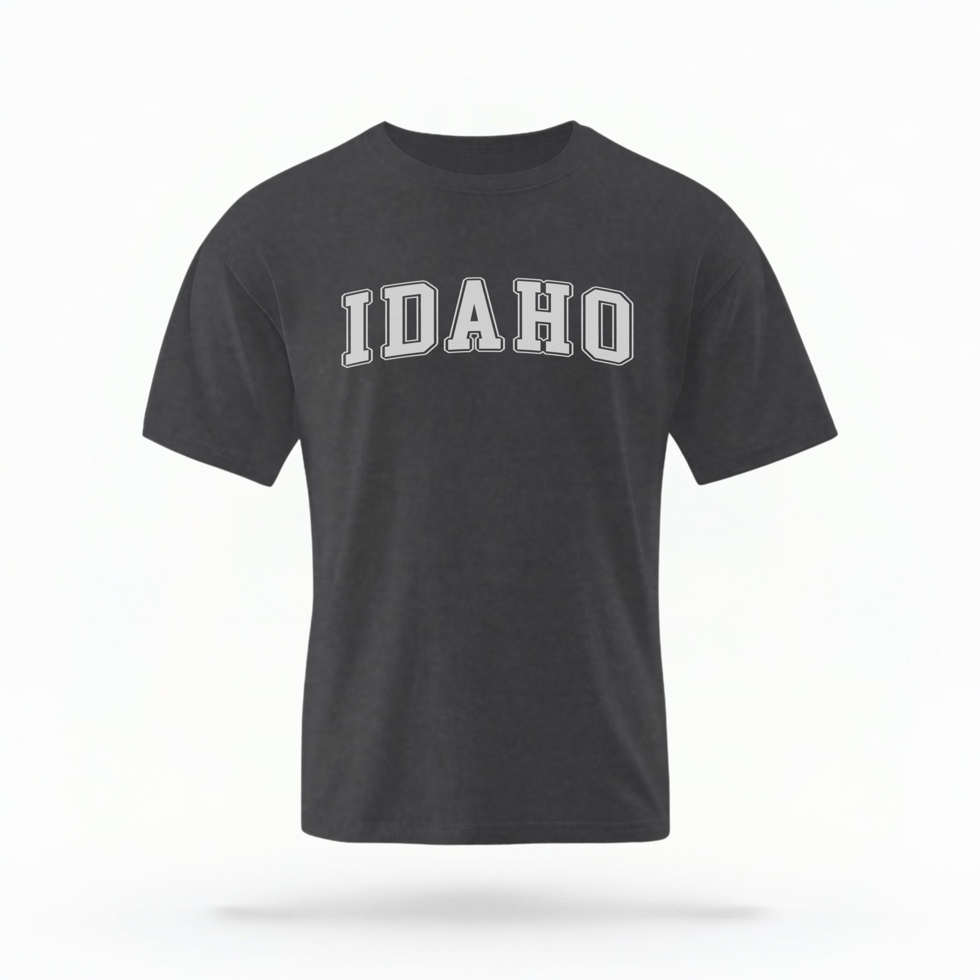 The Pepper Unisex Idaho Varsity Comfort Colors T-shirt lays flat on a white background. The Idaho graphic is in bold white in a varsity offset style.