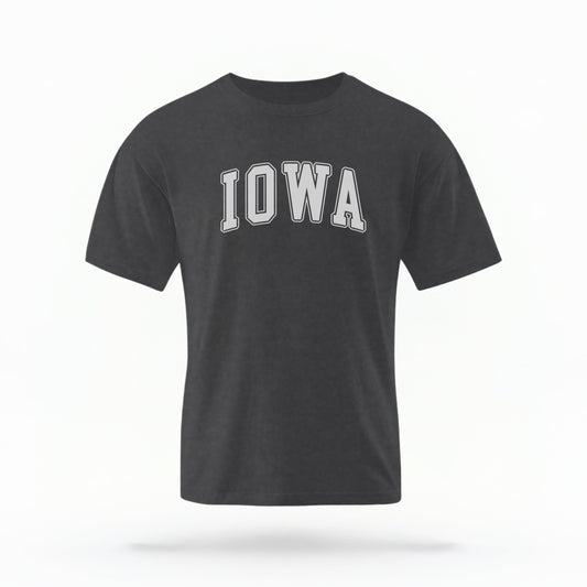 The Pepper Unisex Iowa Varsity Comfort Colors T-shirt lays flat on a white background. The Iowa graphic is in bold white in a varsity offset style.