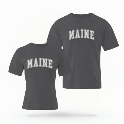 The Pepper Unisex Maine Varsity Comfort Colors T-shirt lays flat on a white background. The Maine graphic is in bold white in a varsity offset style.