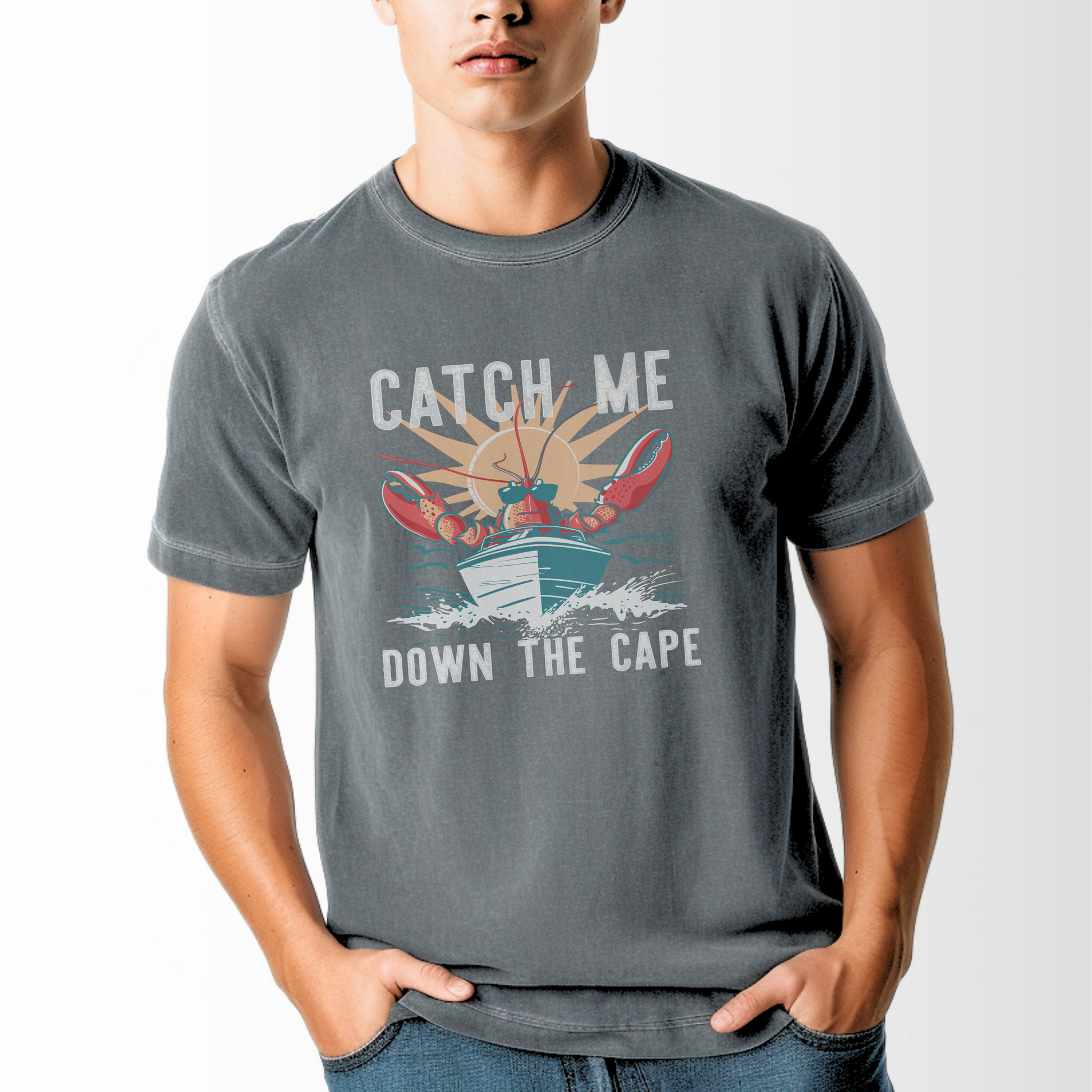 The Pepper Adult Unisex Catch Me Down The Cape Comfort Colors T-shirt lays flat on a white background. The ﻿Catch Me Down The Cape﻿ graphic is in bold multicolor in a Vintage style.