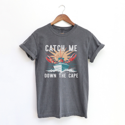 The Pepper Adult Unisex Catch Me Down The Cape Comfort Colors T-shirt lays flat on a white background. The ﻿Catch Me Down The Cape﻿ graphic is in bold Lifestyle in a Vintage style.