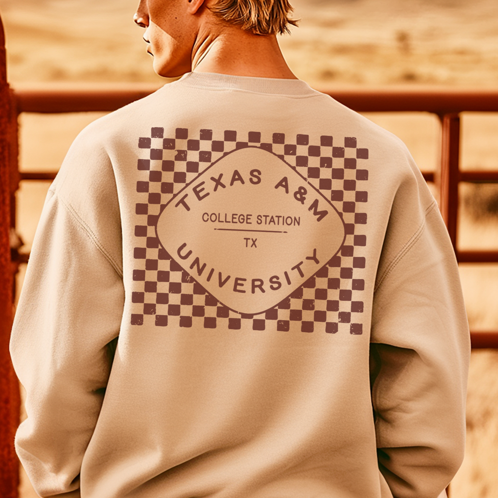 A model wears the sand Texas A&M Crewneck Sweatshirt. The graphic contains a retro checkered pattern. 