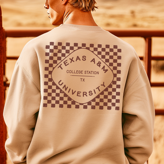 A model wears the sand Texas A&M Crewneck Sweatshirt. The graphic contains a retro checkered pattern. 
