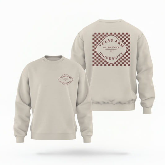 A sand Texas A&M Crewneck Sweatshirt lays flat on white background. The graphic contains a retro checkered pattern. 