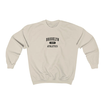 The Sand Brooklyn Athletics Crewneck Sweatshirt lays flat on a white background. The ﻿Brooklyn Athletics﻿ graphic is in bold Navy in a Varsity style.