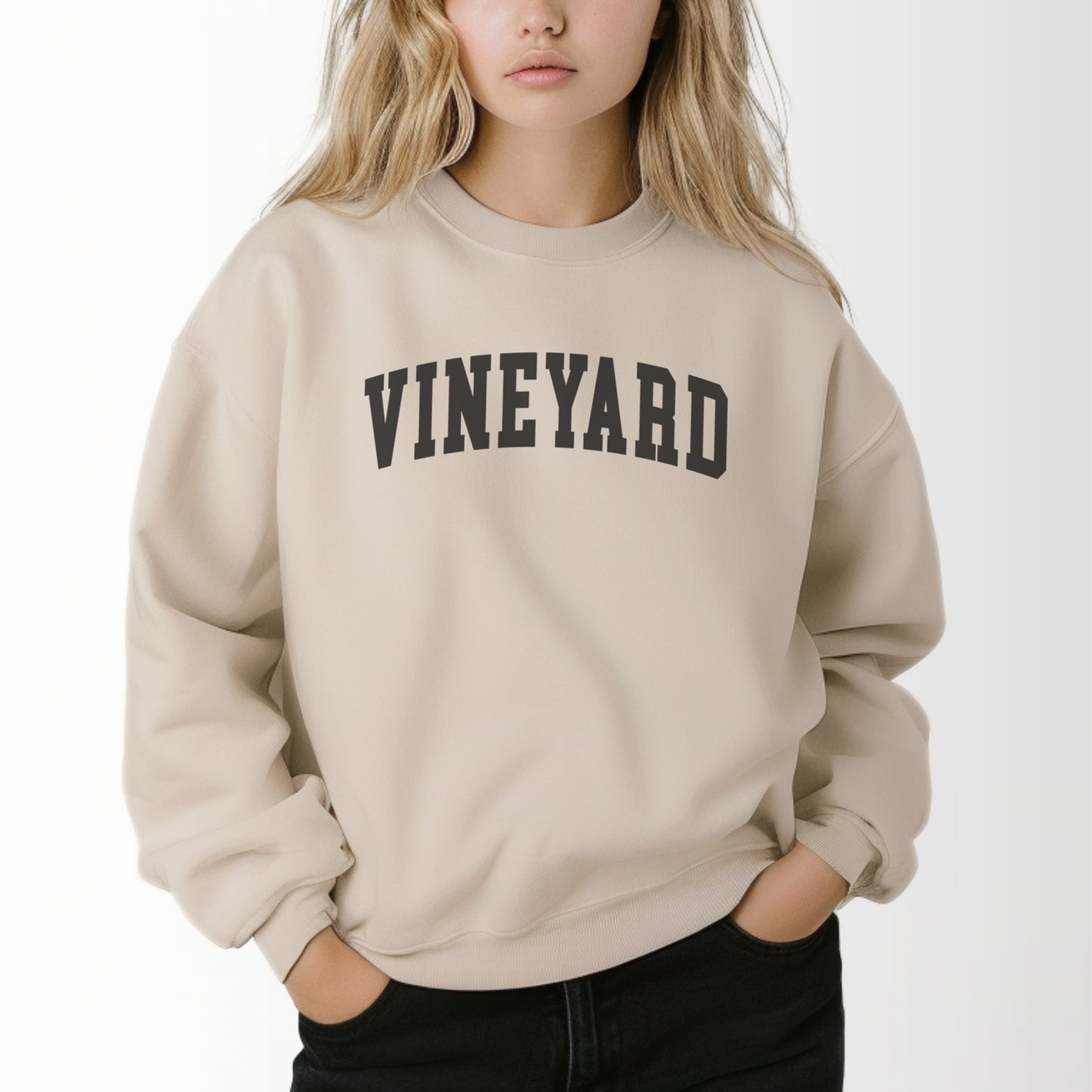 A model wears the Sand Adult Unisex Martha's Vineyard Massachusetts Classic Crewneck Sweatshirt.  The ﻿Martha's Vineyard Massachusetts Classic﻿ graphic is in bold Black in a Varsity style.