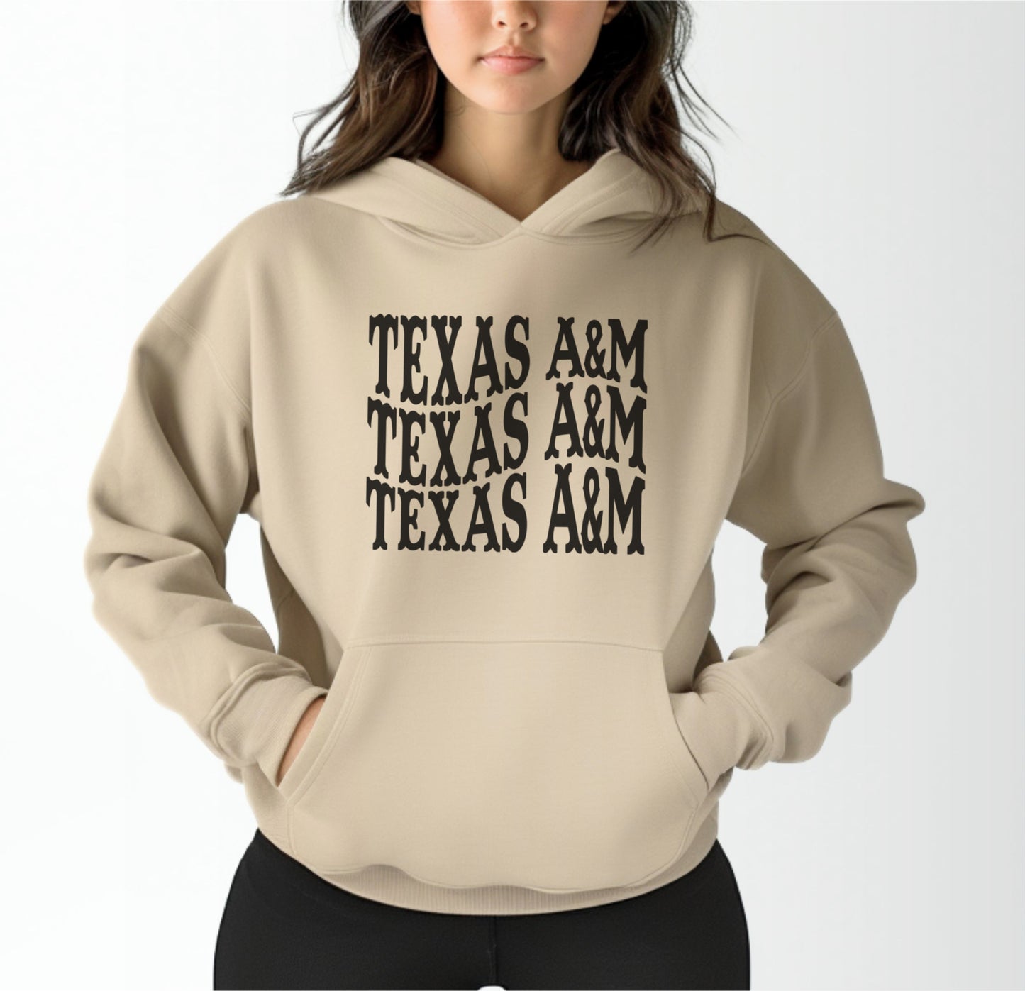 A model wears the Sand Adult Unisex Texas A&M Western Hooded Sweatshirt.  The ﻿Texas A&M Western﻿ graphic is in bold Black in a Western style.